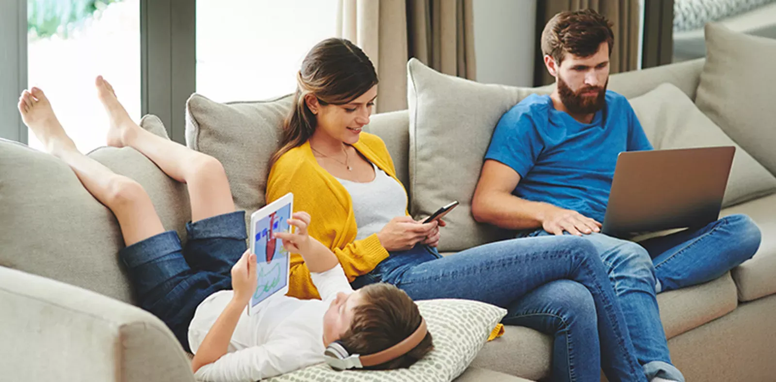 Family gathered on couch with multiple internet devices